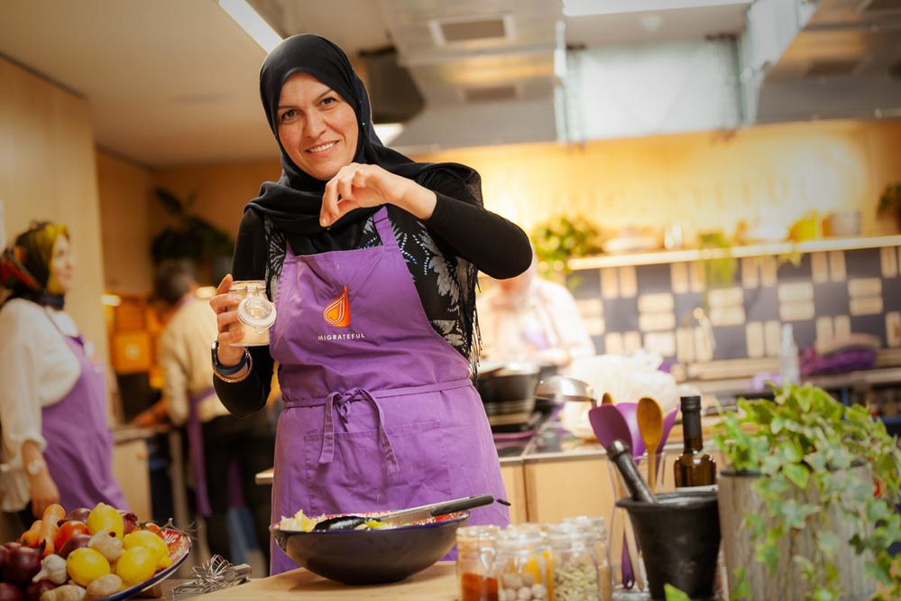Lady with hijab cooking at refugee cookery school