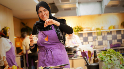 Lady with hijab cooking at refugee cookery school