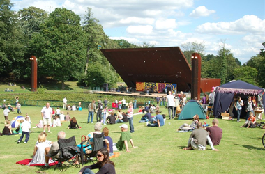 People sitting on grass in front of Crystal Palace Bowl stage
