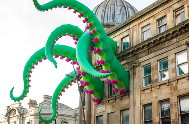 Big green and pink tentacles coming out of city building