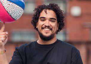 Headshot of man balancing basketball on finger