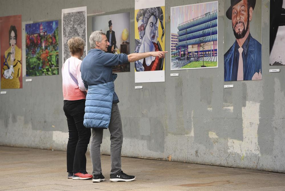 Two people browse a community art gallery